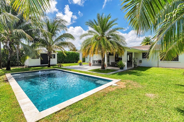 pool featuring a lawn, a patio, and an outdoor structure