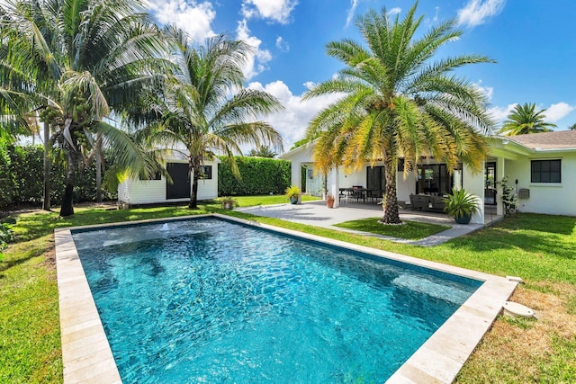 pool with a lawn, an outbuilding, and a patio