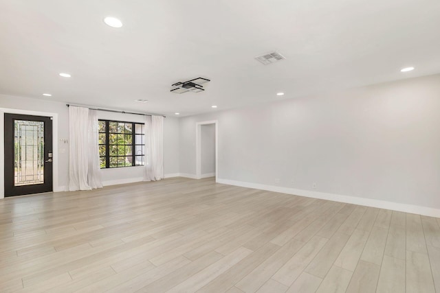 spare room with baseboards, light wood-type flooring, visible vents, and recessed lighting