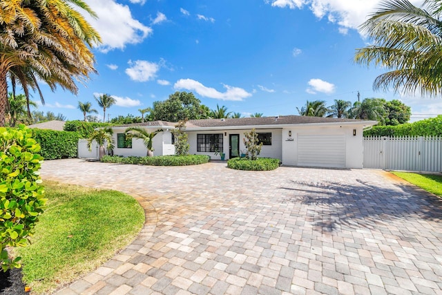 view of front of house featuring a gate, a garage, stucco siding, fence, and curved driveway