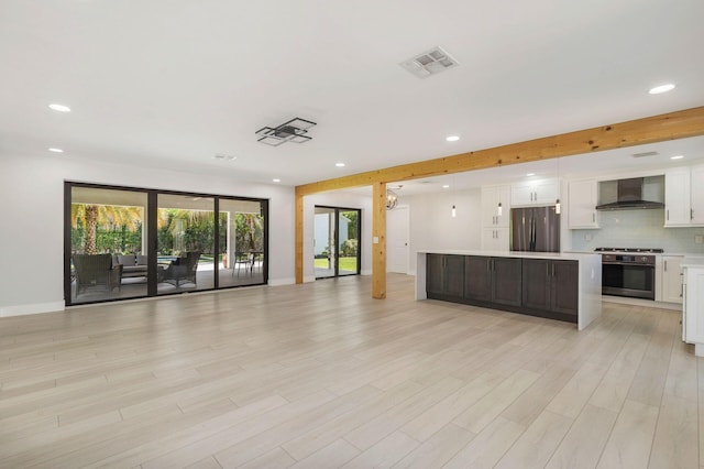 kitchen featuring stainless steel appliances, a center island, wall chimney range hood, and recessed lighting