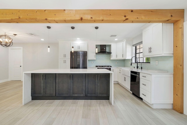 kitchen featuring freestanding refrigerator, wall chimney exhaust hood, dishwasher, decorative backsplash, and a center island
