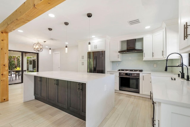 kitchen featuring wall chimney range hood, white cabinetry, and appliances with stainless steel finishes