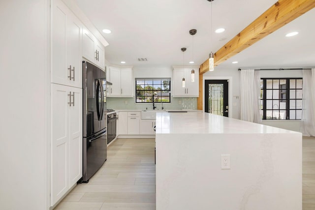 kitchen with a sink, freestanding refrigerator, recessed lighting, light countertops, and a center island