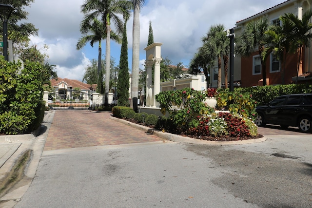 9825 Baywinds Dr Unit 1208, West Palm Beach, FL 33411 - view of asphalt road with a gate, curbs, and street lights