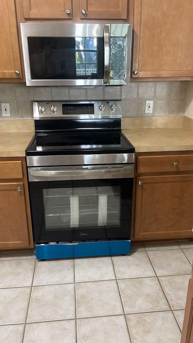 9825 Baywinds Dr Unit 1208, West Palm Beach, FL 33411 - kitchen featuring stainless steel appliances, decorative backsplash, light countertops, and brown cabinetry