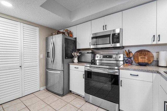 5031 Wiles Rd Unit 104, Coconut Creek, FL 33073 - kitchen with a textured ceiling, light tile patterned floors, light countertops, white cabinets, and stainless steel appliances