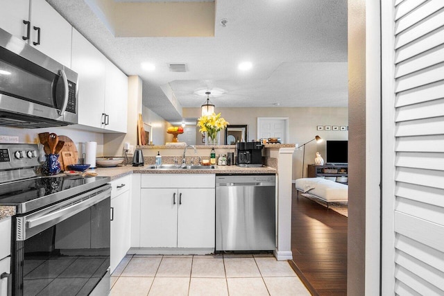 5031 Wiles Rd Unit 104, Coconut Creek, FL 33073 - kitchen featuring visible vents, a peninsula, white cabinets, a sink, and stainless steel appliances