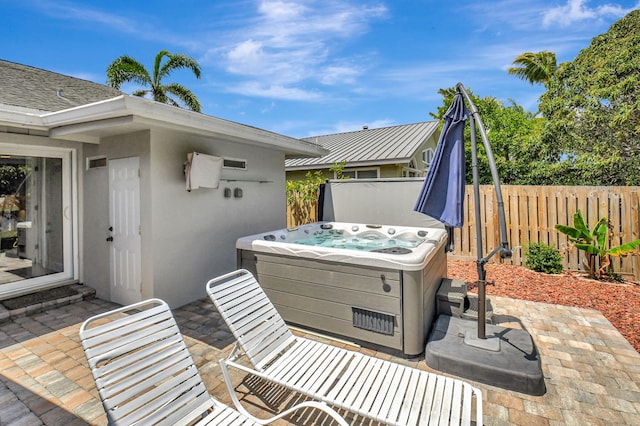 view of patio / terrace featuring a hot tub and fence