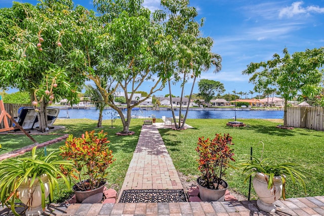 view of community featuring fence, a water view, and a yard
