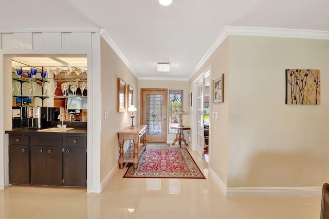 foyer entrance featuring crown molding, baseboards, bar area, and light tile patterned floors
