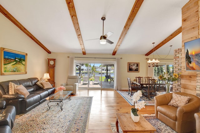 living room featuring vaulted ceiling with beams, light wood-style flooring, ceiling fan with notable chandelier, and a healthy amount of sunlight