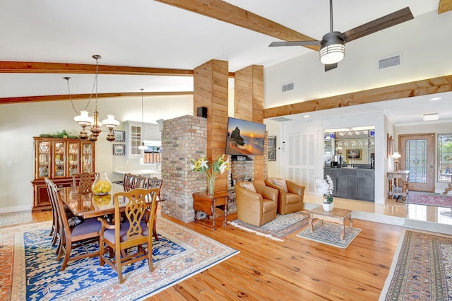 dining room with visible vents, hardwood / wood-style floors, a fireplace, and beamed ceiling