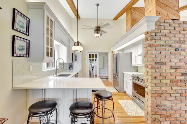 kitchen featuring a peninsula, light wood-style floors, light countertops, a sink, and appliances with stainless steel finishes