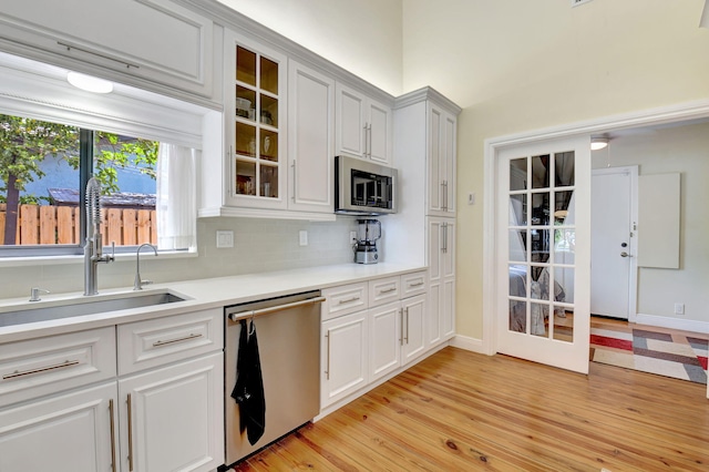 147 Oregon Ln, Boca Raton, FL 33487 - kitchen featuring stainless steel appliances, a sink, light countertops, light wood finished floors, and decorative backsplash