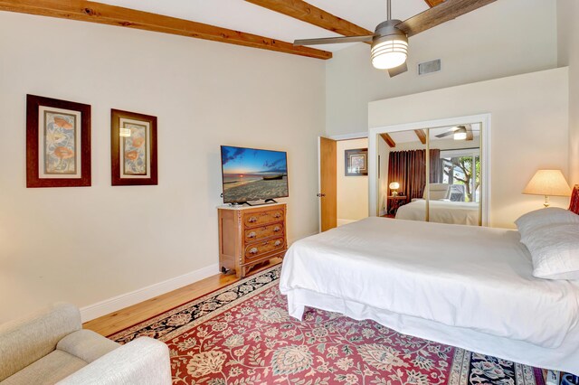bedroom with ceiling fan, beam ceiling, light wood-style floors, baseboards, and visible vents