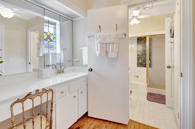 full bath with vanity, ceiling fan, wood finished floors, and a stall shower
