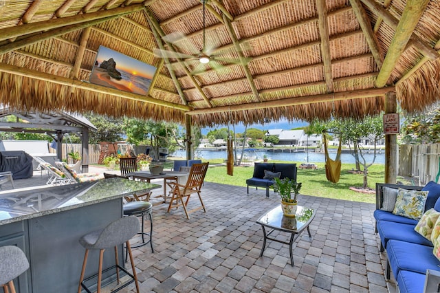 view of patio with a water view, a gazebo, fence, and outdoor dry bar