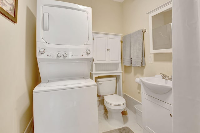 bathroom featuring stacked washing maching and dryer, baseboards, vanity, and toilet