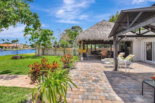 view of patio with fence, outdoor dining area, a gazebo, and a water view