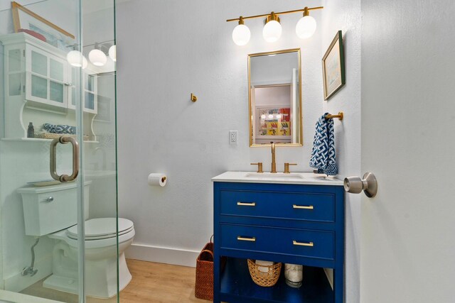 full bathroom with vanity, toilet, baseboards, wood finished floors, and a stall shower