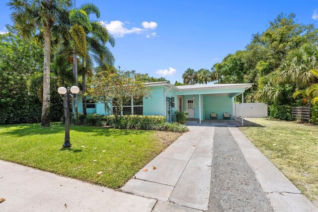 view of front of house with fence, a front yard, stucco siding, an attached carport, and concrete driveway