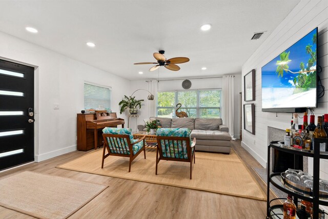 living room with light wood-style floors, a ceiling fan, baseboards, recessed lighting, and visible vents