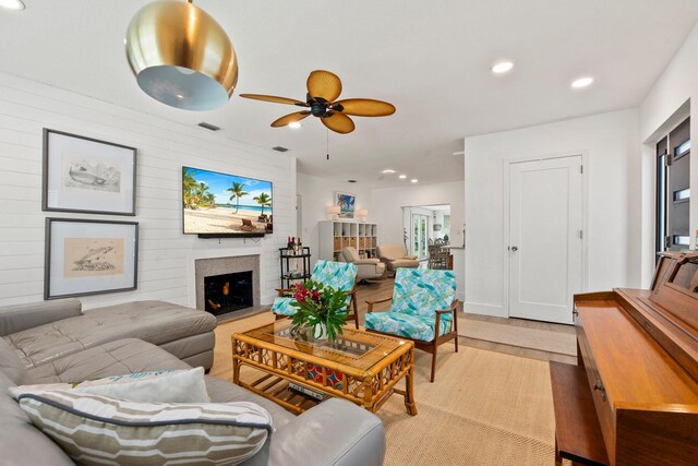 living room featuring ceiling fan, recessed lighting, a lit fireplace, light wood-type flooring, and visible vents