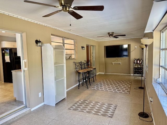 interior space with baseboards, crown molding, tile patterned floors, and wood walls