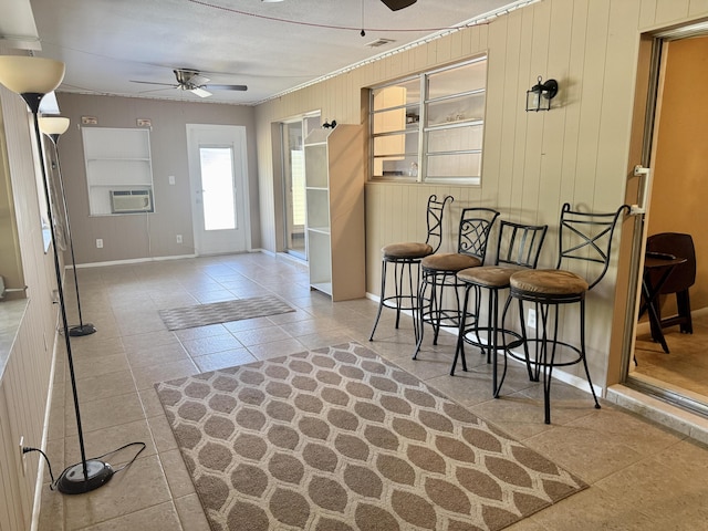 tiled foyer entrance with baseboards, ornamental molding, wooden walls, and ceiling fan