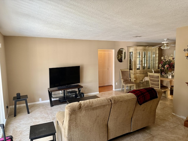tiled living room featuring baseboards, ceiling fan, and a textured ceiling