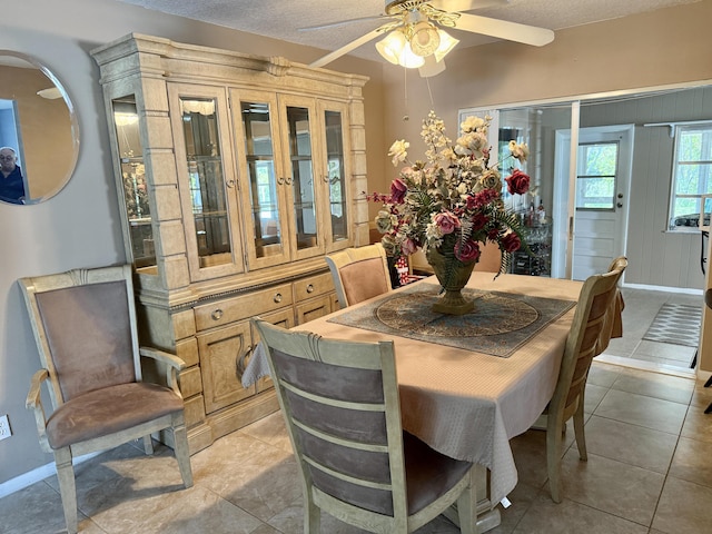dining room with a ceiling fan, baseboards, light tile patterned floors, and a textured ceiling