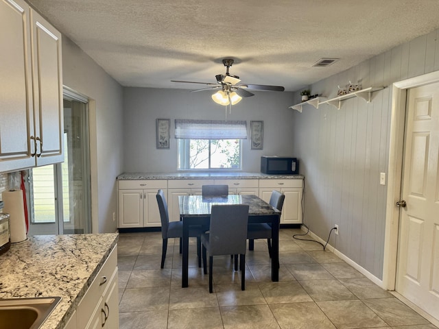 dining room featuring a ceiling fan, a textured ceiling, visible vents, baseboards, and light tile patterned flooring