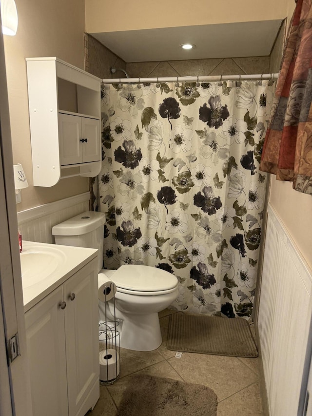 full bath featuring toilet, vanity, curtained shower, tile patterned flooring, and wainscoting