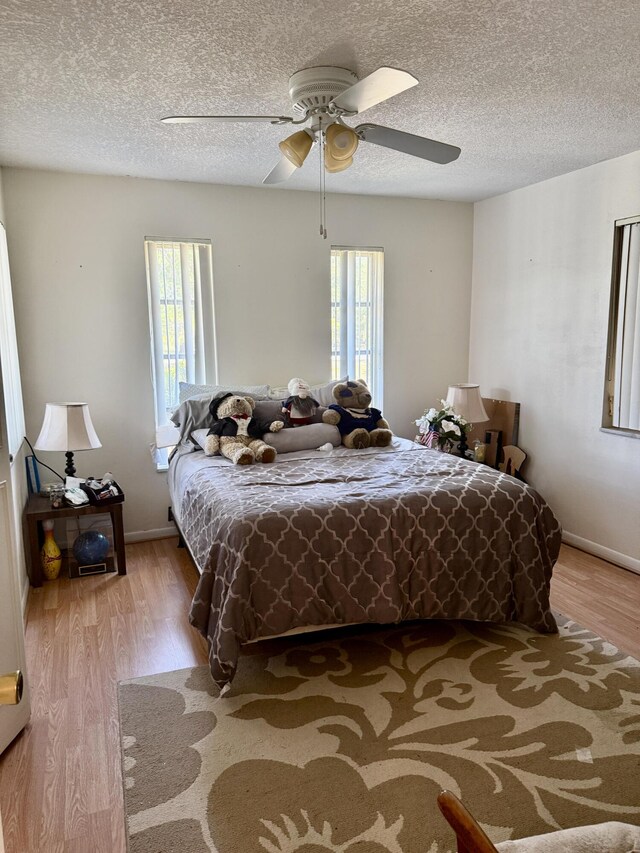 bedroom with multiple windows, a textured ceiling, and wood finished floors