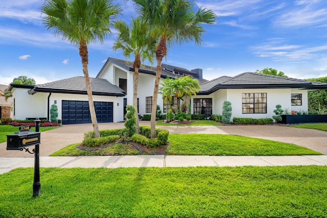 view of front facade with stucco siding, an attached garage, driveway, and a front yard