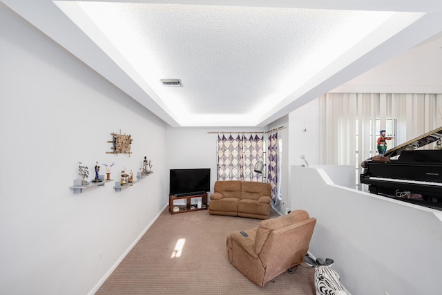living area featuring a textured ceiling, carpet, baseboards, a tray ceiling, and visible vents