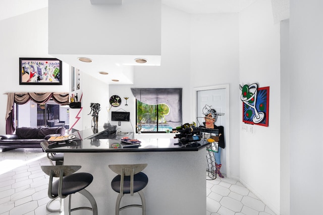 kitchen featuring light tile patterned floors, a high ceiling, and a kitchen bar