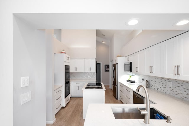 kitchen with light countertops, white cabinets, a sink, and black appliances