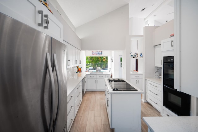 kitchen featuring decorative backsplash, a center island, high vaulted ceiling, freestanding refrigerator, and black electric stovetop