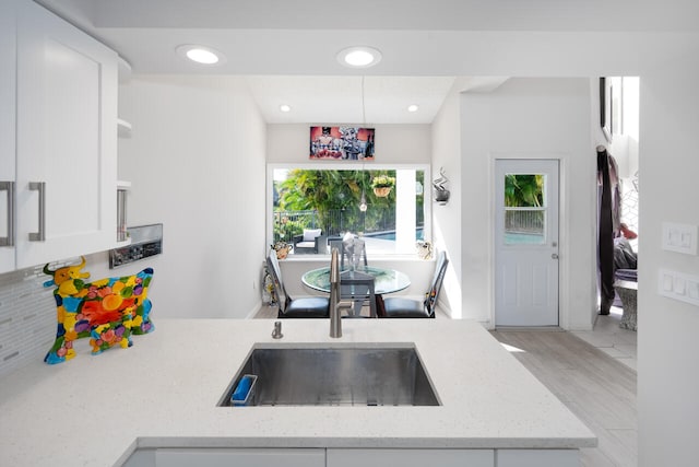 kitchen featuring open shelves, light stone countertops, white cabinetry, tasteful backsplash, and a sink