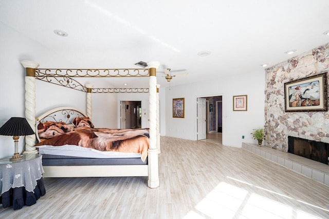 bedroom with visible vents, wood finished floors, and a tiled fireplace