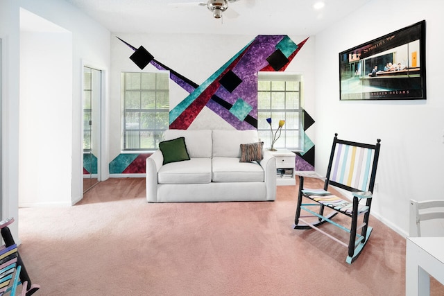 carpeted living area with baseboards and ceiling fan