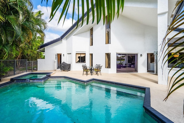 view of pool featuring a pool with connected hot tub, fence, and a patio area