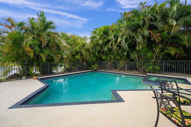 view of swimming pool with a patio, a pool with connected hot tub, and fence