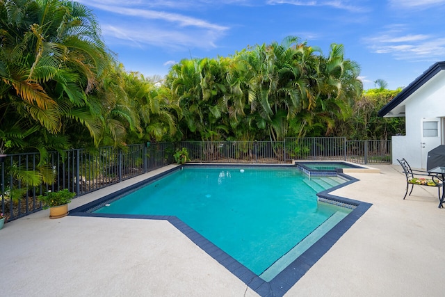 view of swimming pool featuring fence, a patio, and a pool with connected hot tub