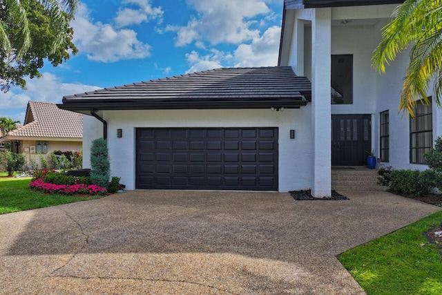 view of side of home with a garage, driveway, and stucco siding