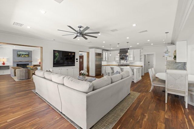 103 River Dr, Tequesta, FL 33469 - living area featuring a ceiling fan, crown molding, dark wood-style flooring, recessed lighting, and a fireplace