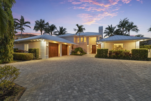 103 River Dr, Tequesta, FL 33469 - view of front of home with a garage, a standing seam roof, stucco siding, metal roof, and driveway