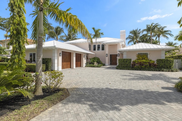 103 River Dr, Tequesta, FL 33469 - view of front of home with an attached garage, stucco siding, metal roof, driveway, and a standing seam roof